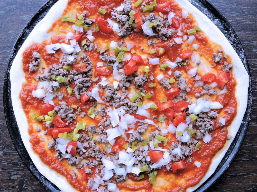 hamburger pizza, toppings added, ready for the oven