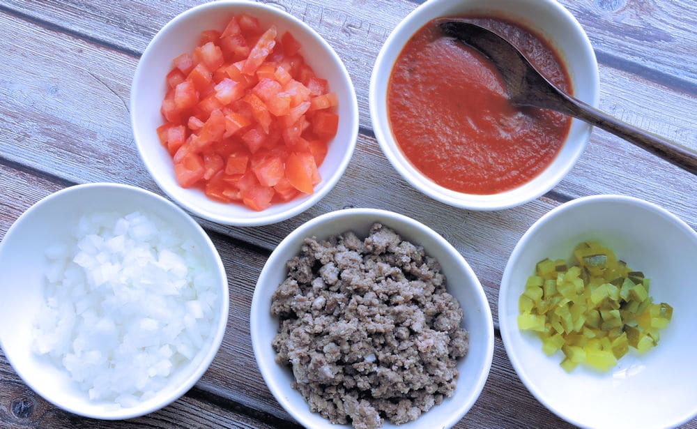 ingredients of hamburger pizza in separate bowls on a countertop