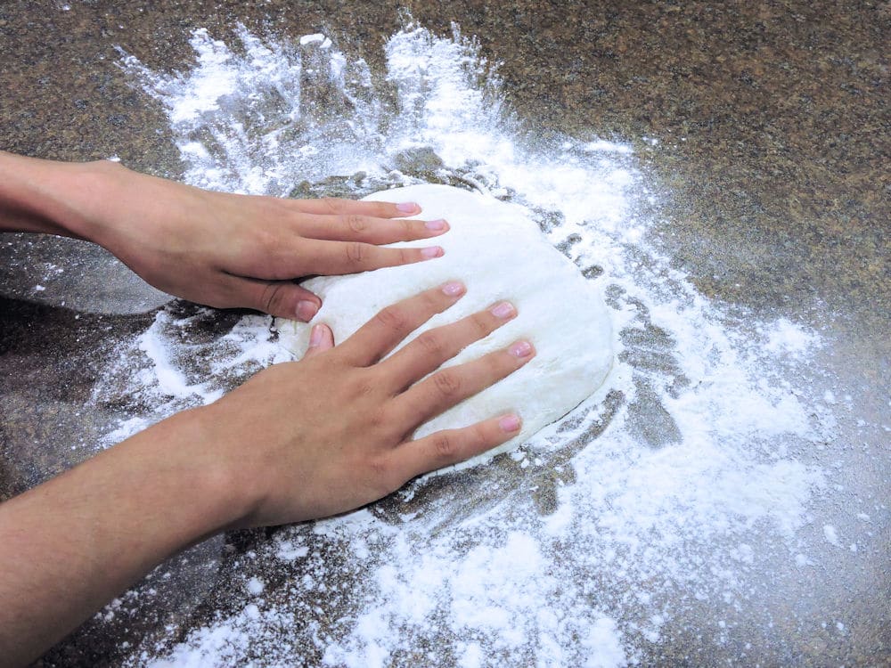 pressing the pizza dough into a flat surface