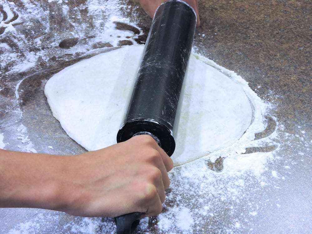 rolling out the pizza dough with a rolling pin
