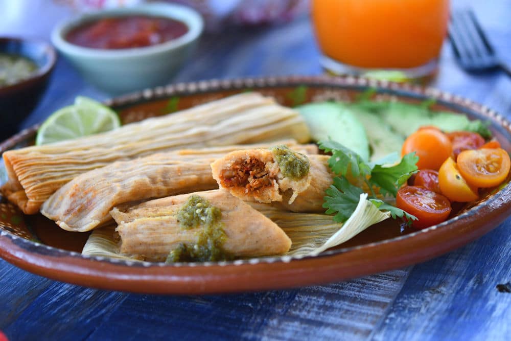 24Bite: Plate of pork tamales served with tomato salad and lime slices