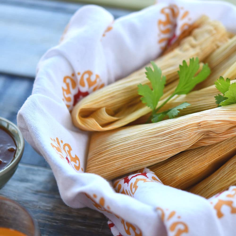 A basket of freshly made pork tamales, still in the husk