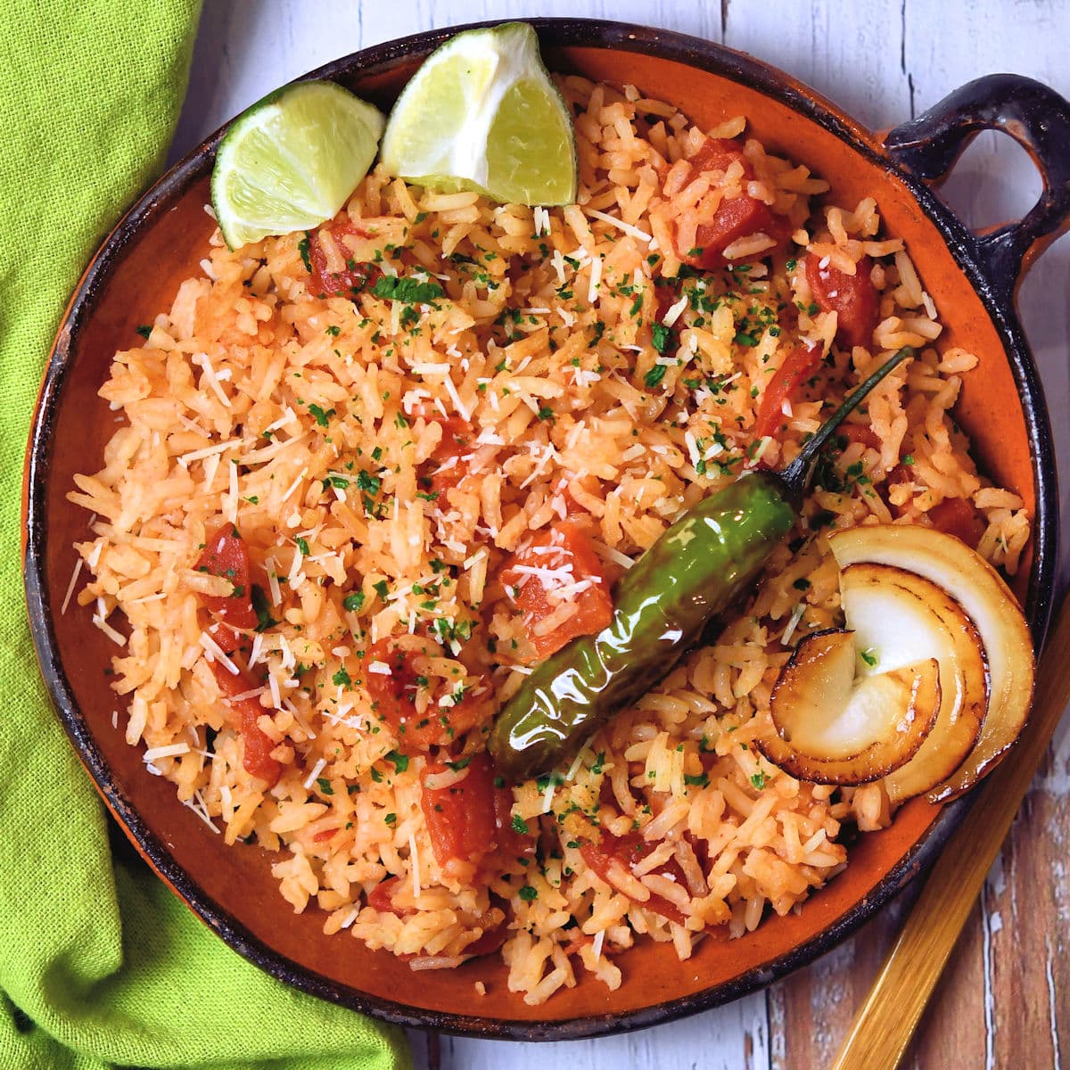 one handled bowl filled with Spanish rice, a sauteed onion ring and fried whole chile pepper