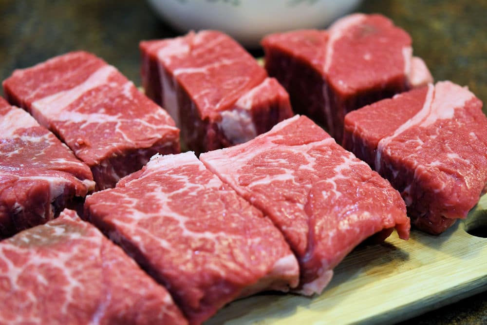 chuck roast on a cutting board, cut into 8 pieces