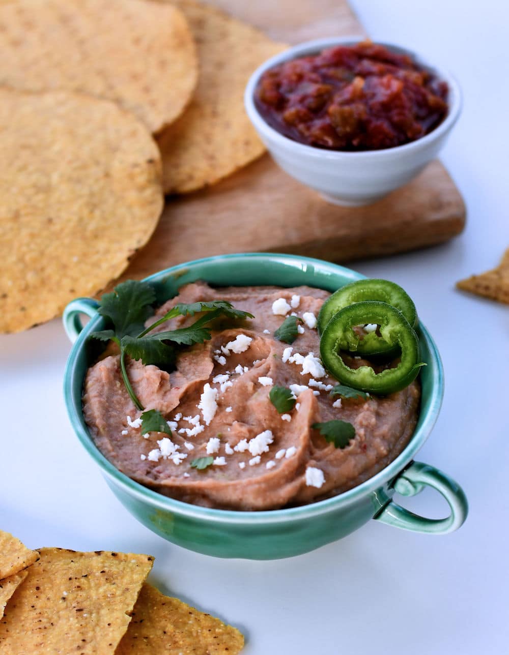 24Bite: Small two-handled bowl with instant pot vegan bean dip shown with tostadas and salsa