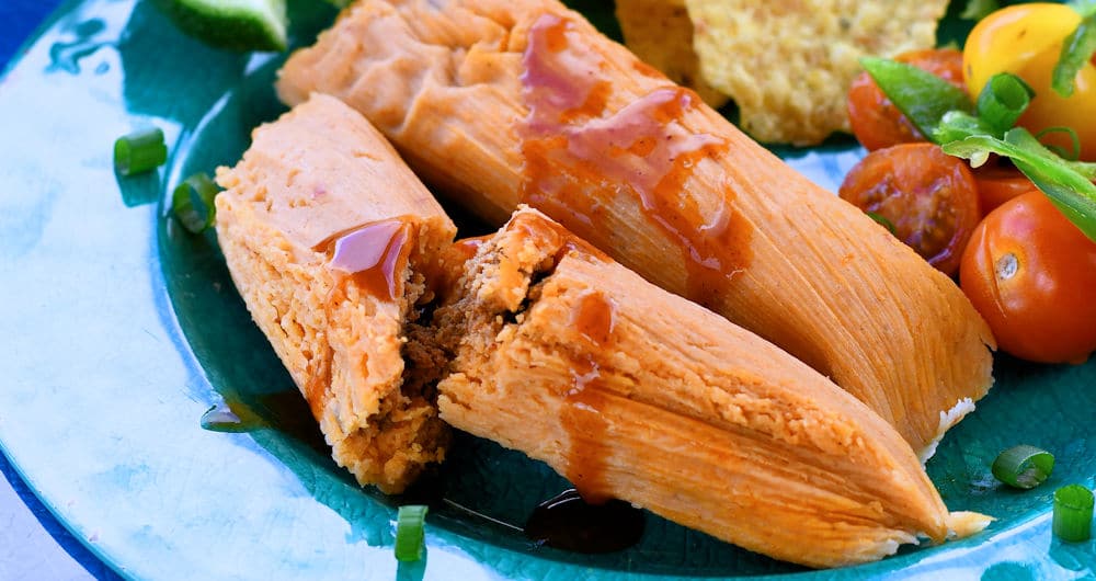 Chorizo tamales on a plate with a tomato salad