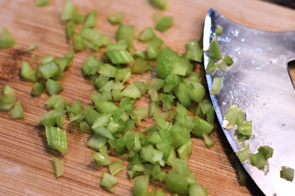 Finely chopped celery with ulu on cutting board
