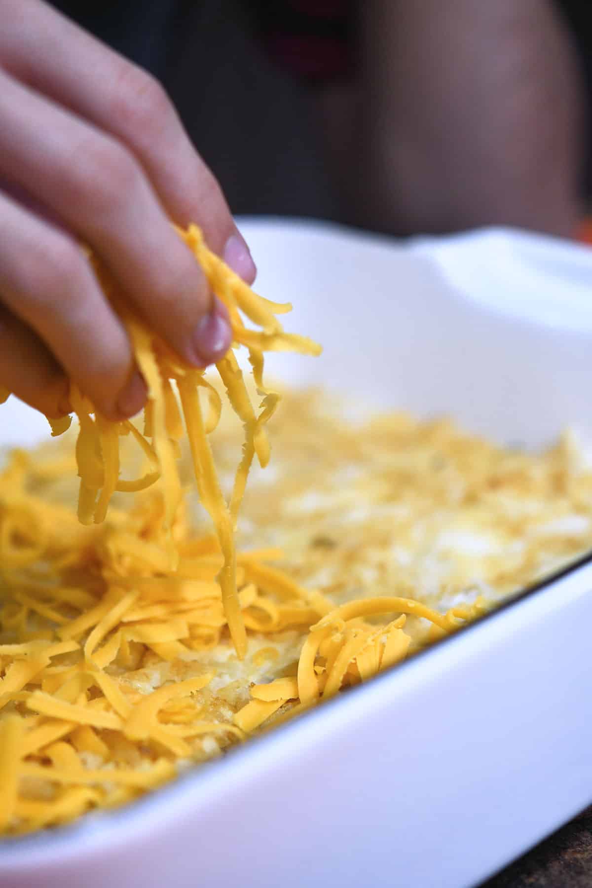 sprinkling shredded cheddar cheese on top of tater tots crust.