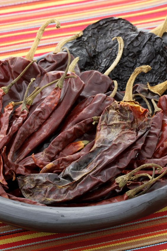 large variety of Mexican dried chiles on a white table