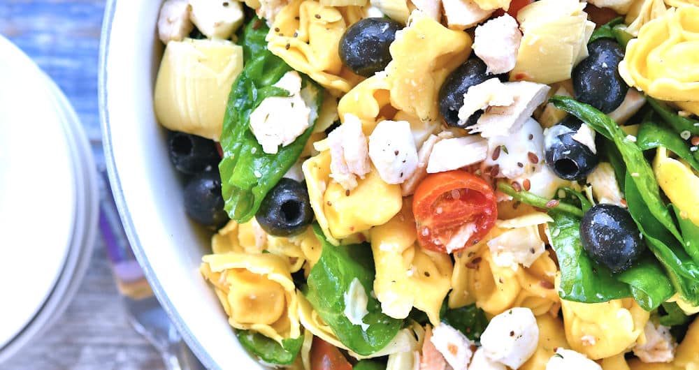cold pasta salad of tortellini and chicken in a white ceramic bowl