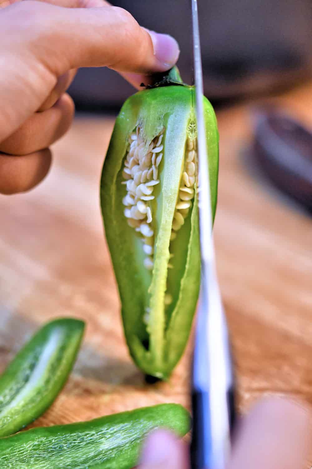 Cutting a jalapeno vertically along the outer edges.