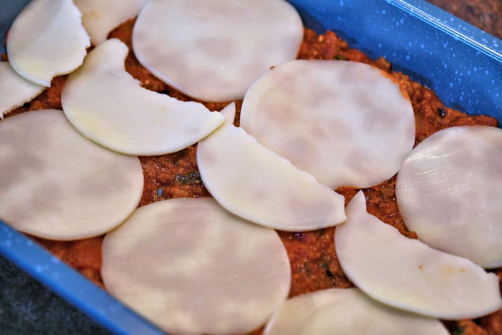 24bite: The start of layering lasagna with Provolone cheese slices over meat sauce