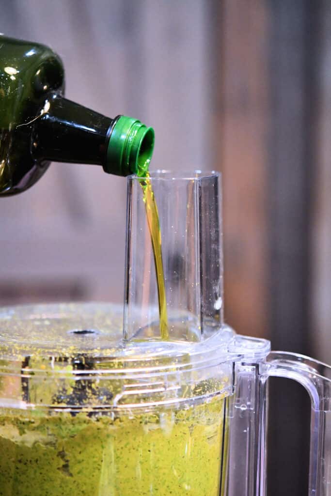 pouring olive oil into food processor