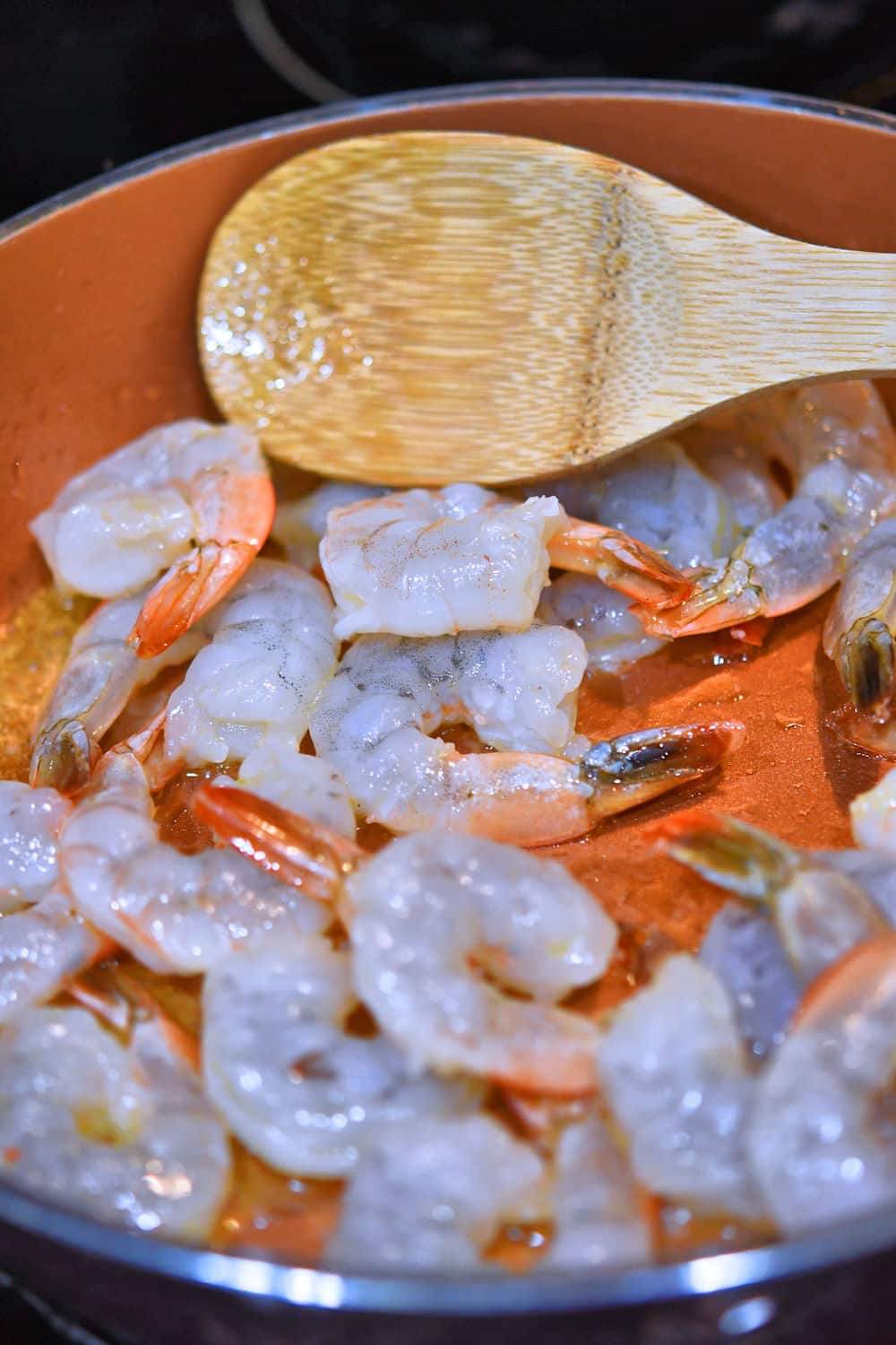 raw shrimp placed in skillet to begin cooking in olive oil
