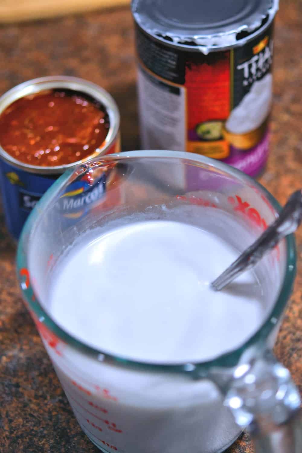 a measuring cup full of coconut cream which has been briskly stirred together to incorporate the solids and liquids