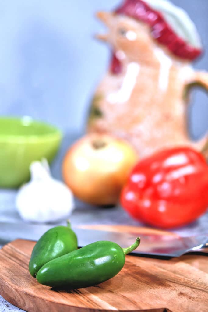 jalapeno peppers on a cutting board with a chef knife.