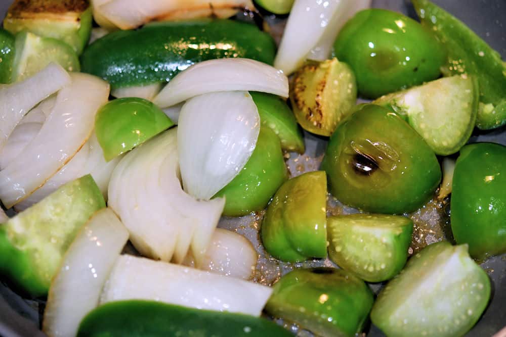 tomatillos, onions and peppers sauteeing in a skillet