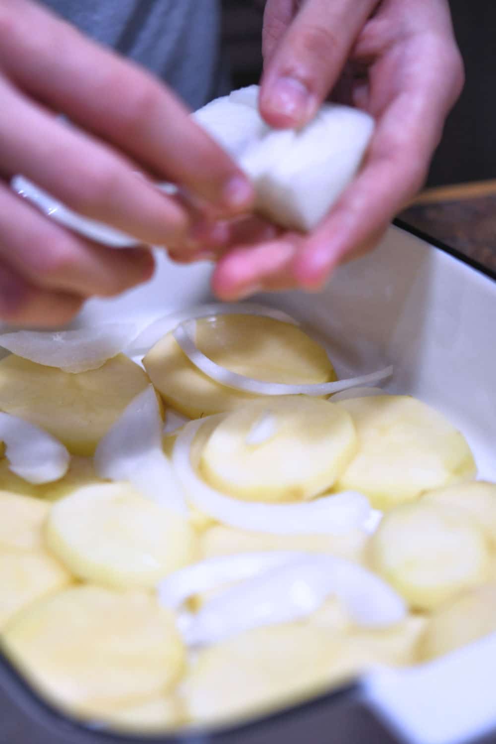 layering the sliced potatoes in the baking pan with a little bit of onion slivers