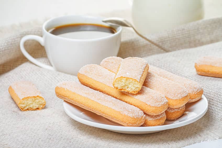 stack of ladyfinger biscuits on a white plate with a cup of coffee to the side. © rustamank via 123rf.com