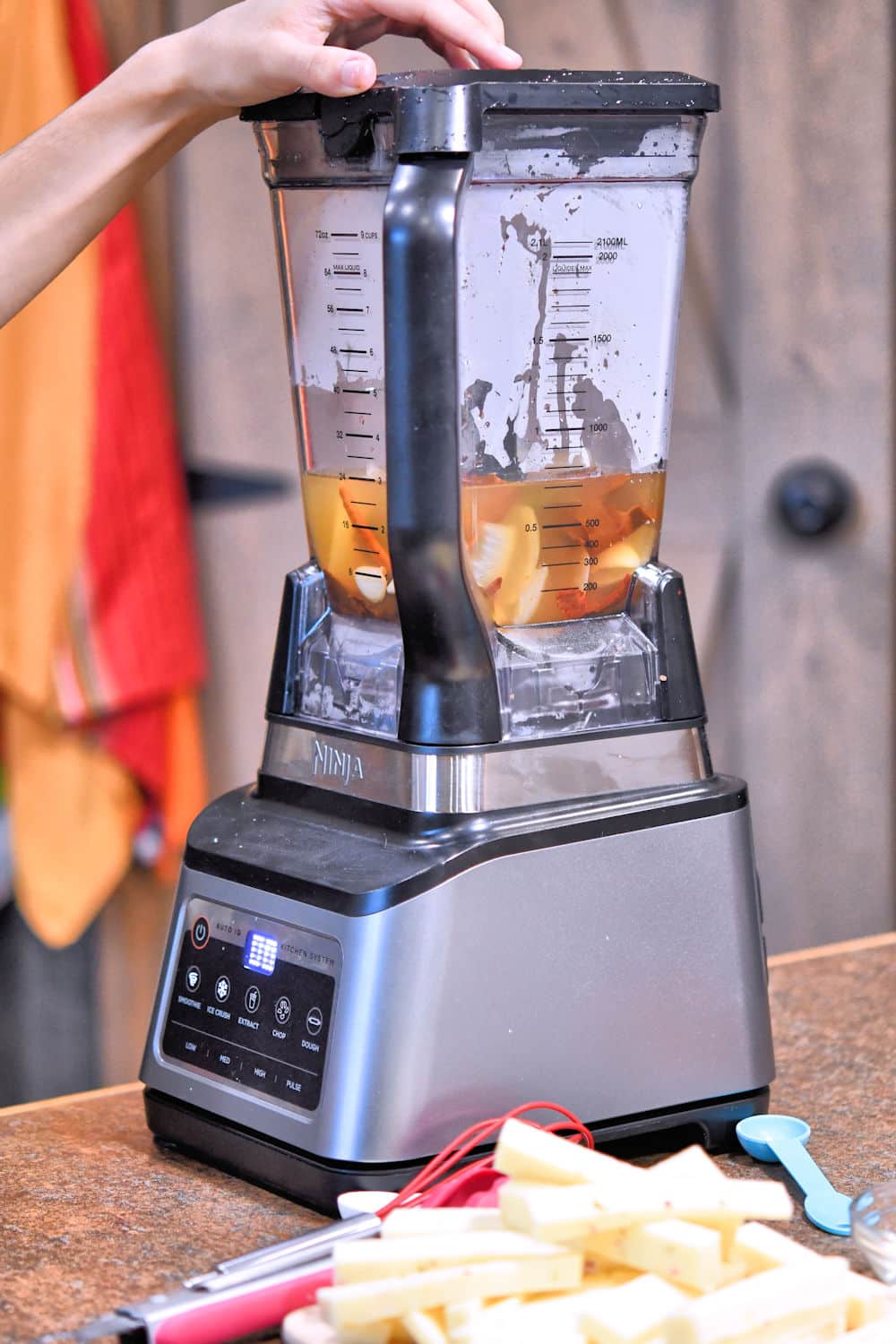 an electric blender with chiles and other vegetables in chicken broth