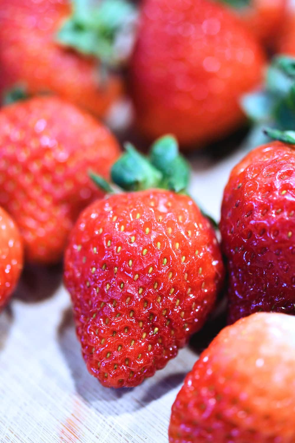 closeup of fresh raw strawberries on a wooden cutting board