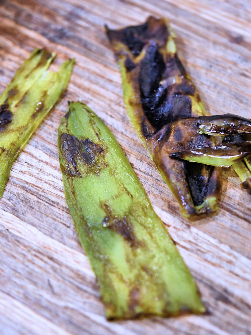 roasted chile peppers on a cutting board with partial charred skin removed