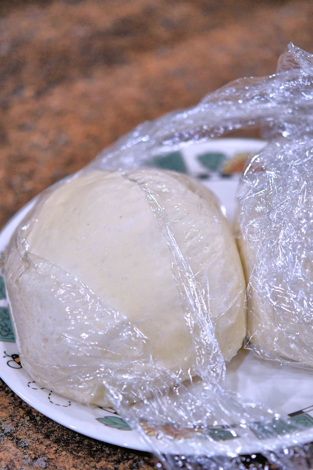 dough balls wrapped in plastic wrap on a plate