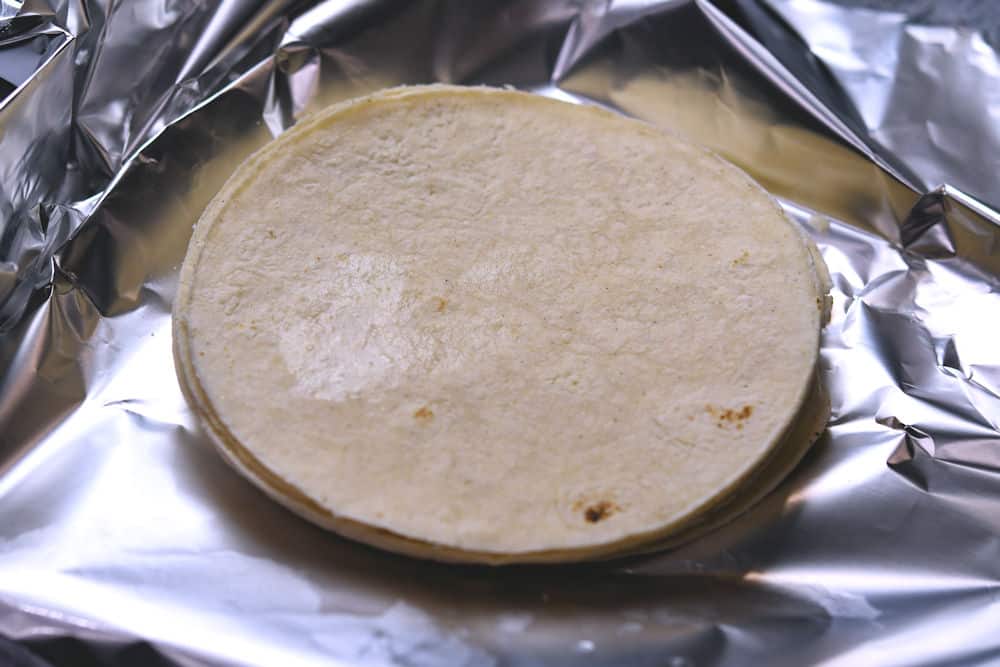preparing corn tortillas to soften in the oven, in aluminum foil