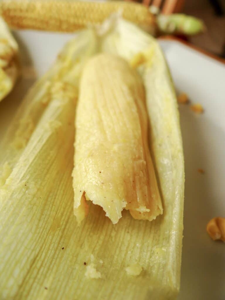 Open sweet corn tamales, sereved on a white plate.