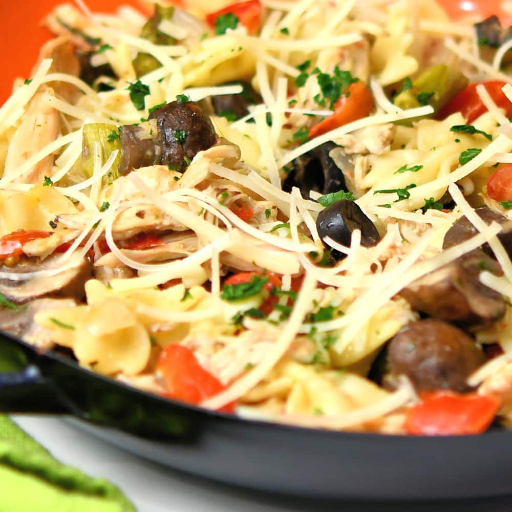 closeup of leftover chicken pasta dinner in an orange and black skillet