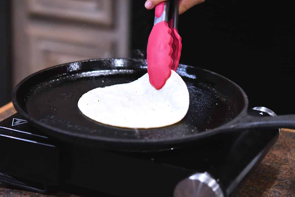 Frying a corn tortilla on a comal or roti pan