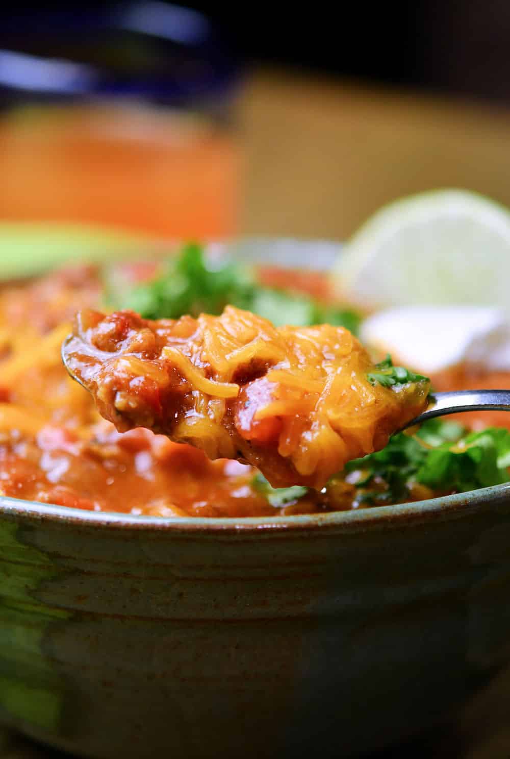 A spoonful of chili covered in shredded cheese