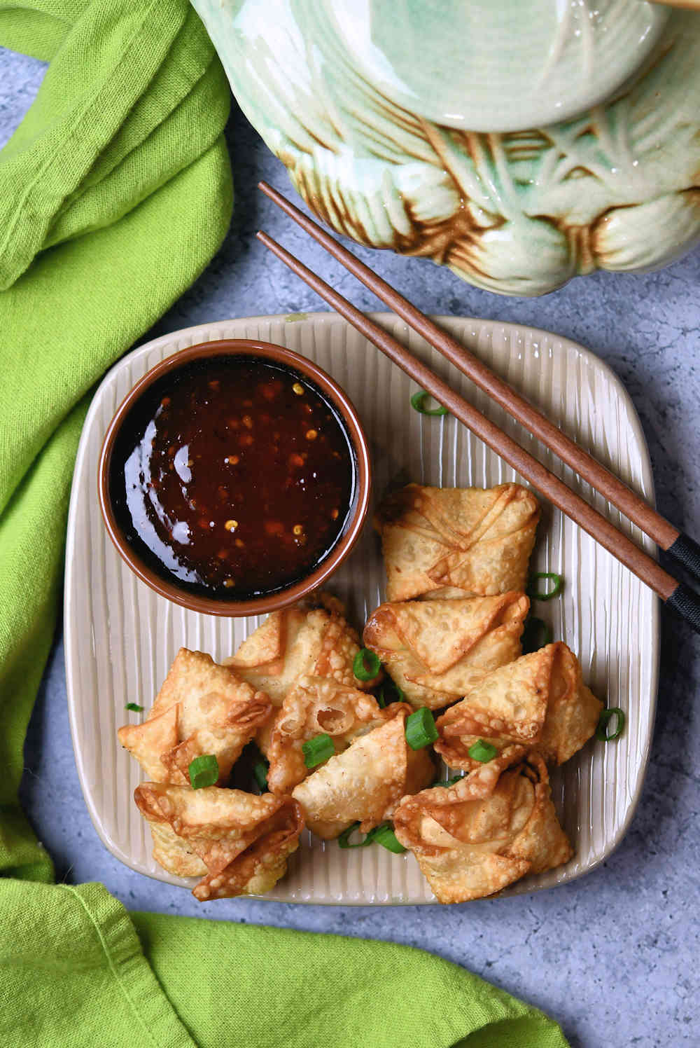 fried shrimp rangoon on a plate with a bowl of sweet chili sauce and chopsticks