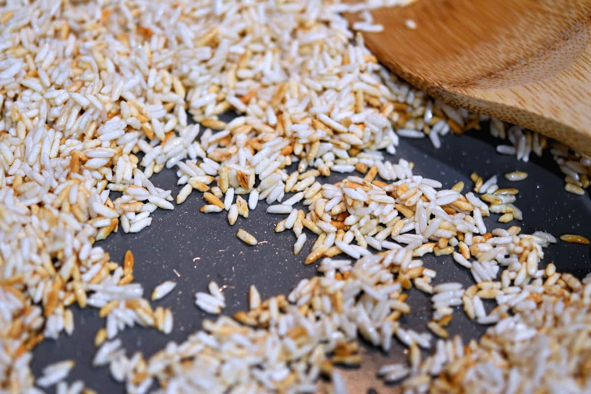 Skillet with sauteed white rice and a wooden spoon.