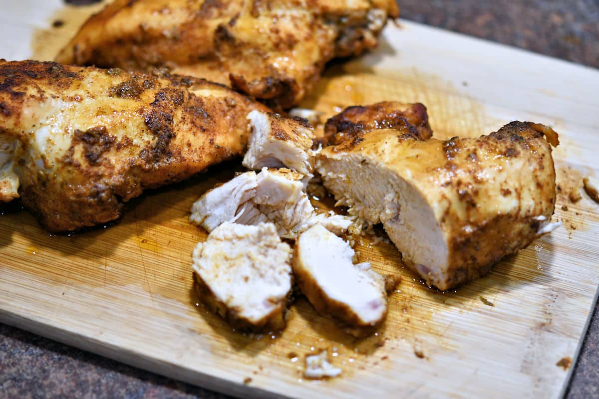 cooked chicken breast on a cutting board, beginning the slicing