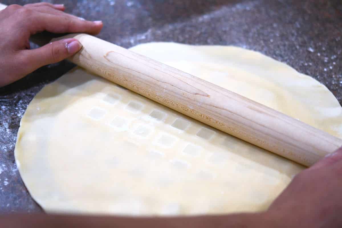 using a rolling pin over the crust top cutter to more easily cut out the shapes