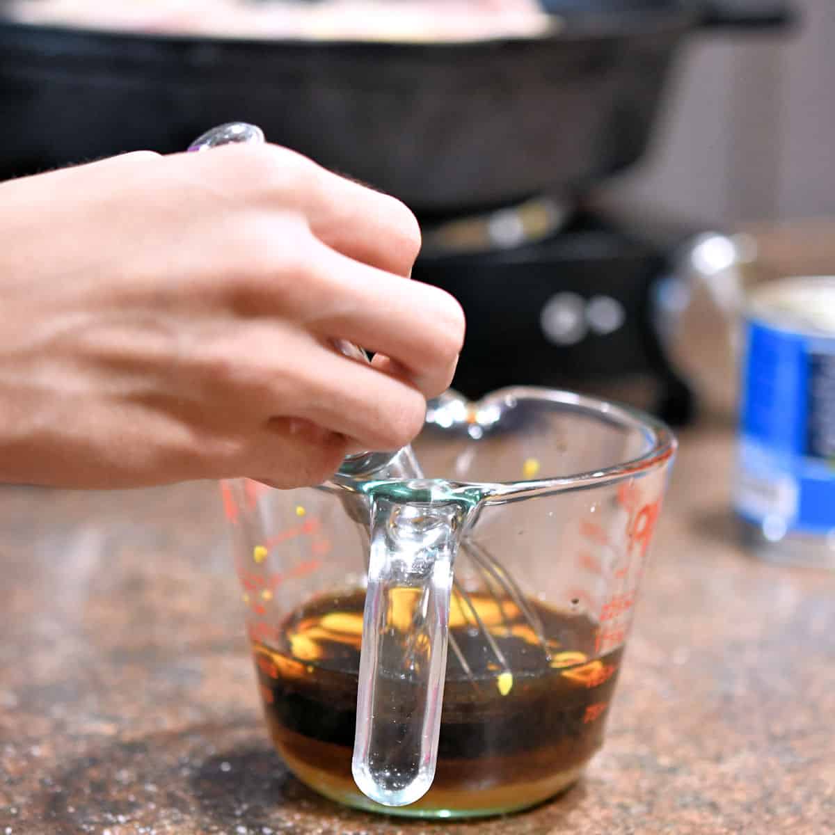 measuring cup with all sauce ingredients being whisked together