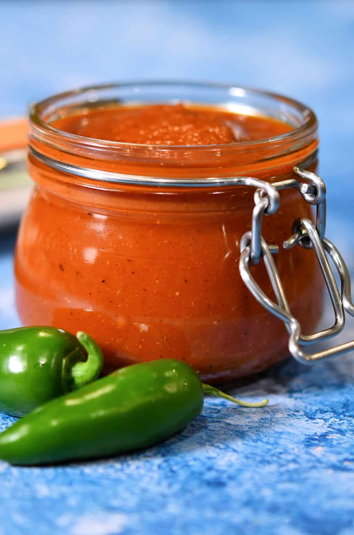 jalapeno ketchup in a glass jar with fresh jalapeno on a countertop