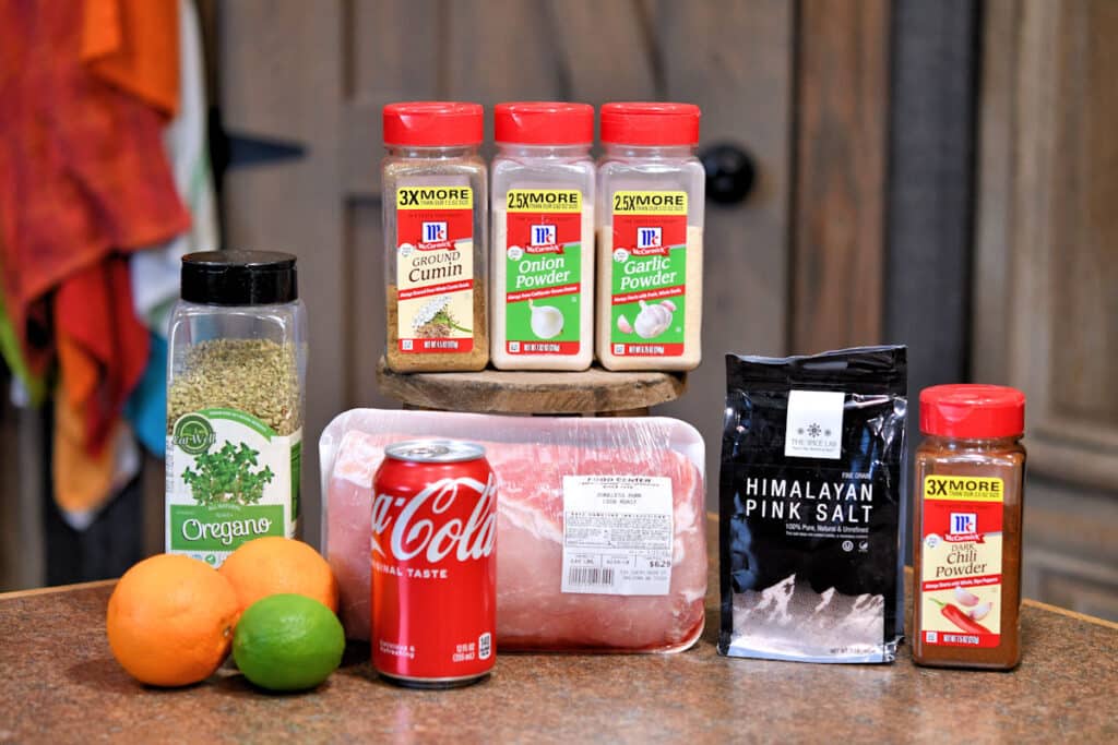 ingredients for pork carnitas from recipe card below, displayed on a countertop