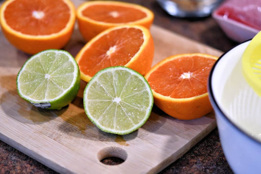 oranges and limes cut in half on a cutting board