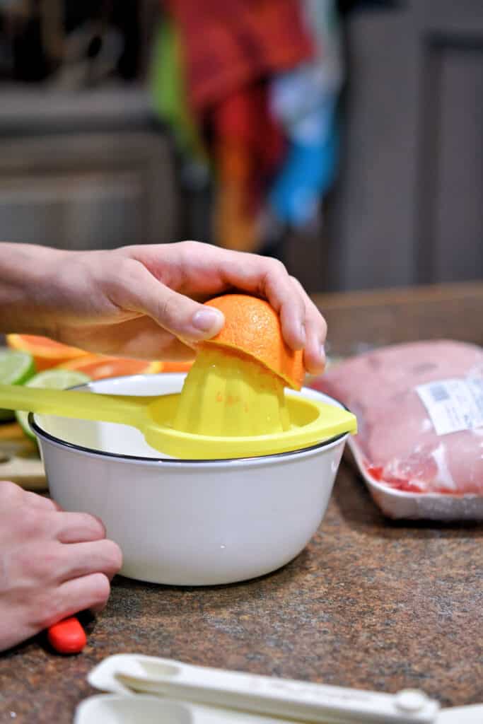 using a juicer tool to get the juice from an orange