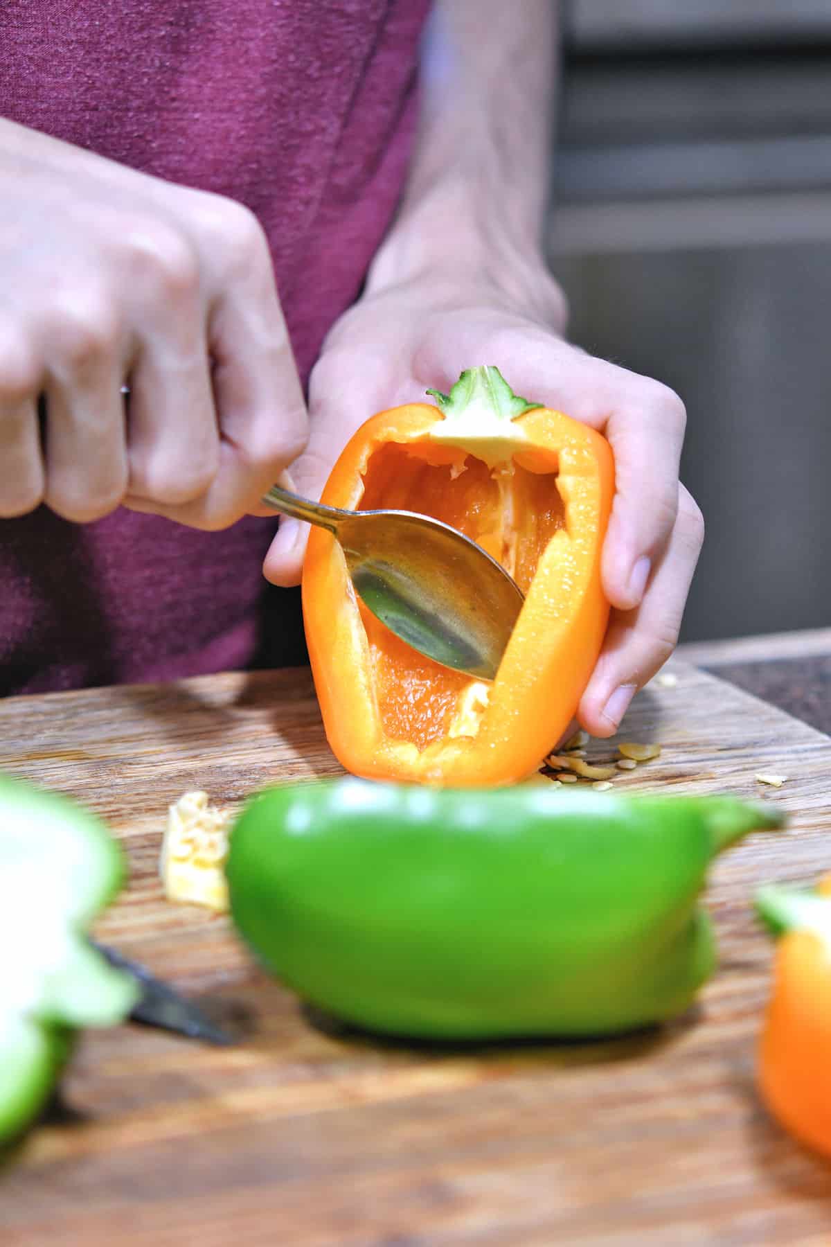 scooping seeds out of the inside of an orange bell pepper