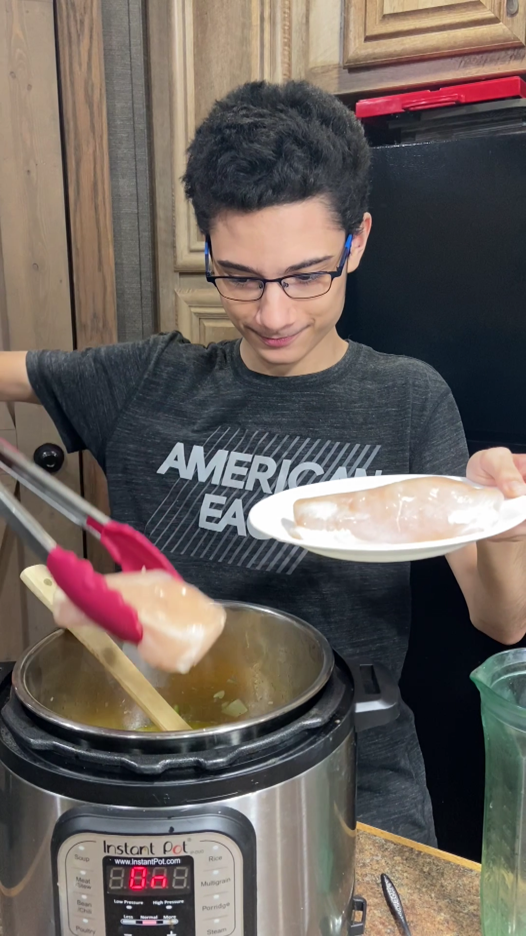 Chef Christian using silicone tongs to add chicken breasts to Instant Pot