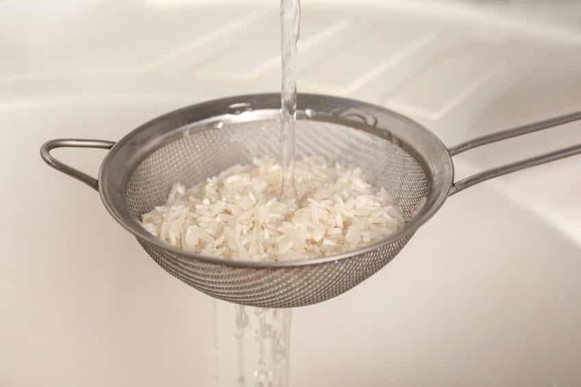 rinsing rice in a strainer with cool water running over it © serezniy via 123rf.com