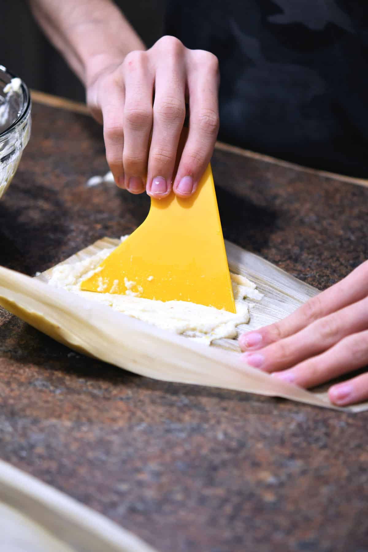 spreading the masa dough on a corn husk.