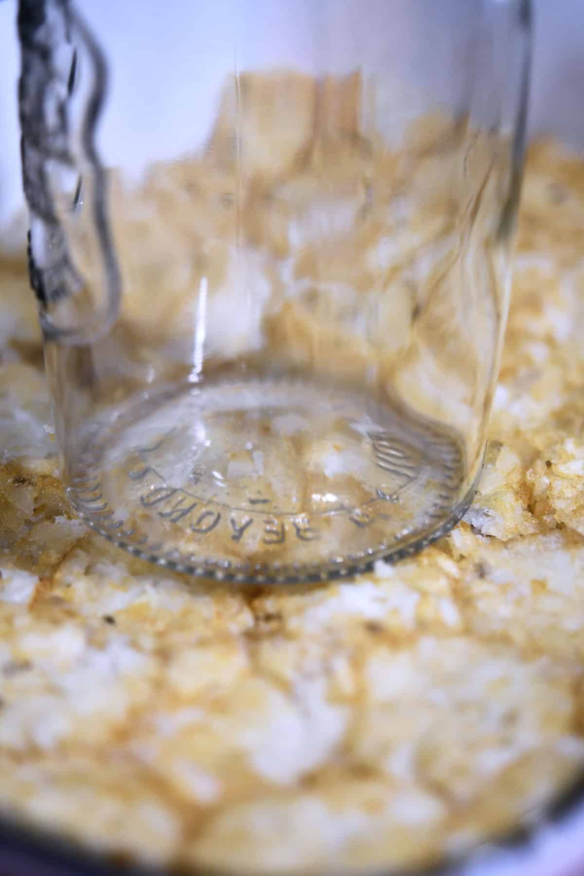 making tater tot crust by using a drinking glass to press them.