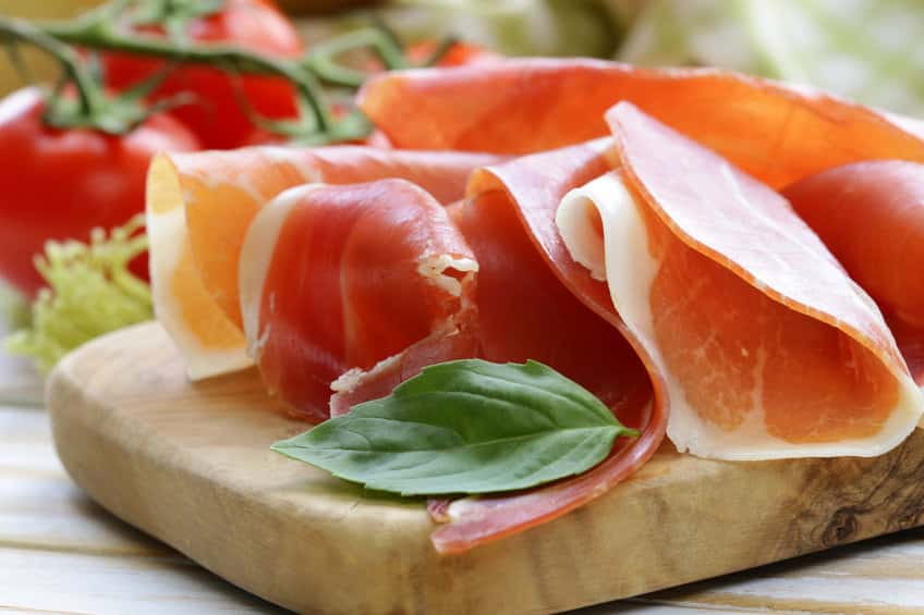 thin slices of prosciutto on a wooden cutting board