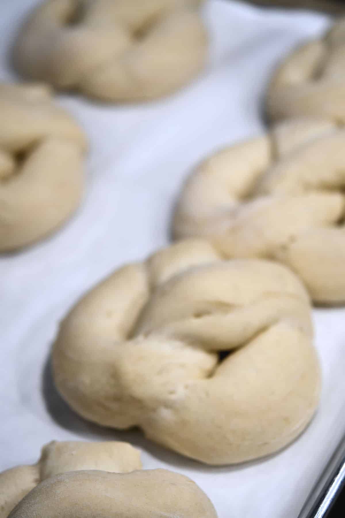 shaped fluffy dough shaped into pretzels on a baking sheet