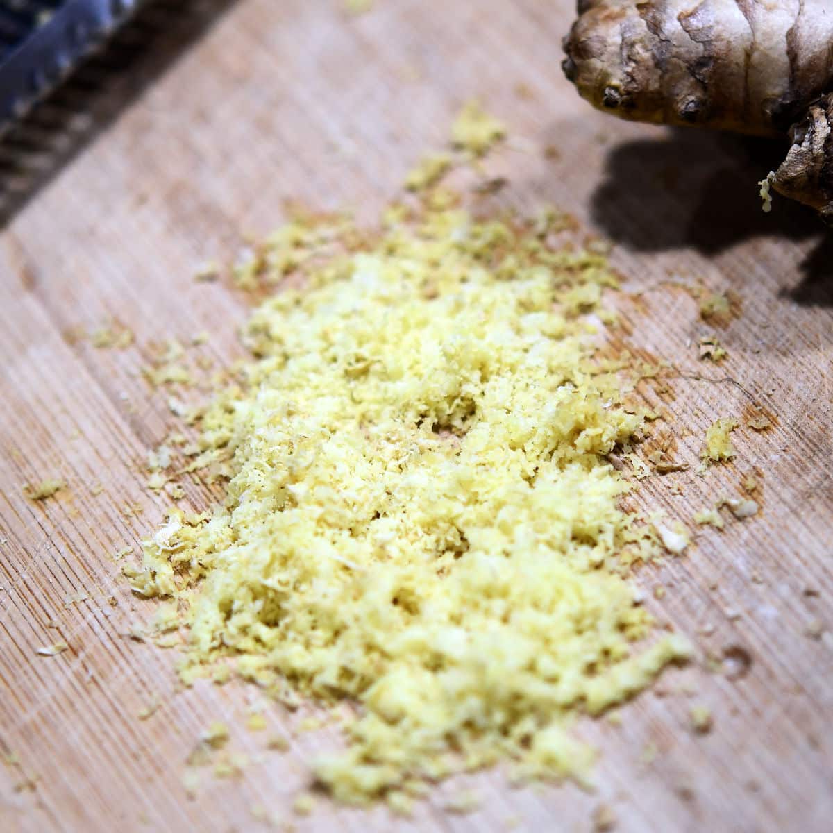freshly grated ginger on a cutting board with a microplane