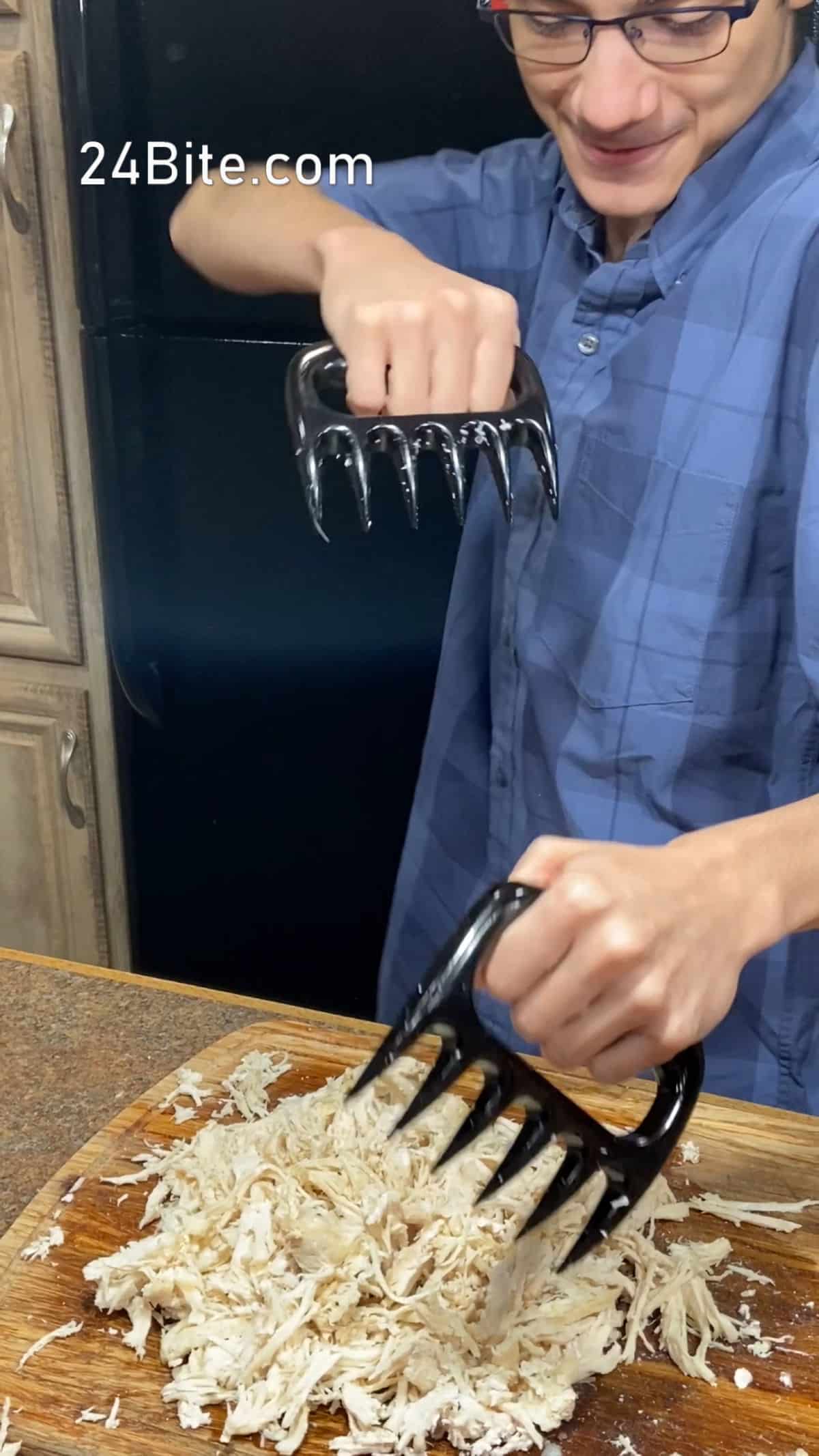 Christian Guzman using meat shredding claws to shred cooked  chicken breast